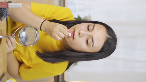 Vertical-video-of-Young-woman-applying-lipstick.